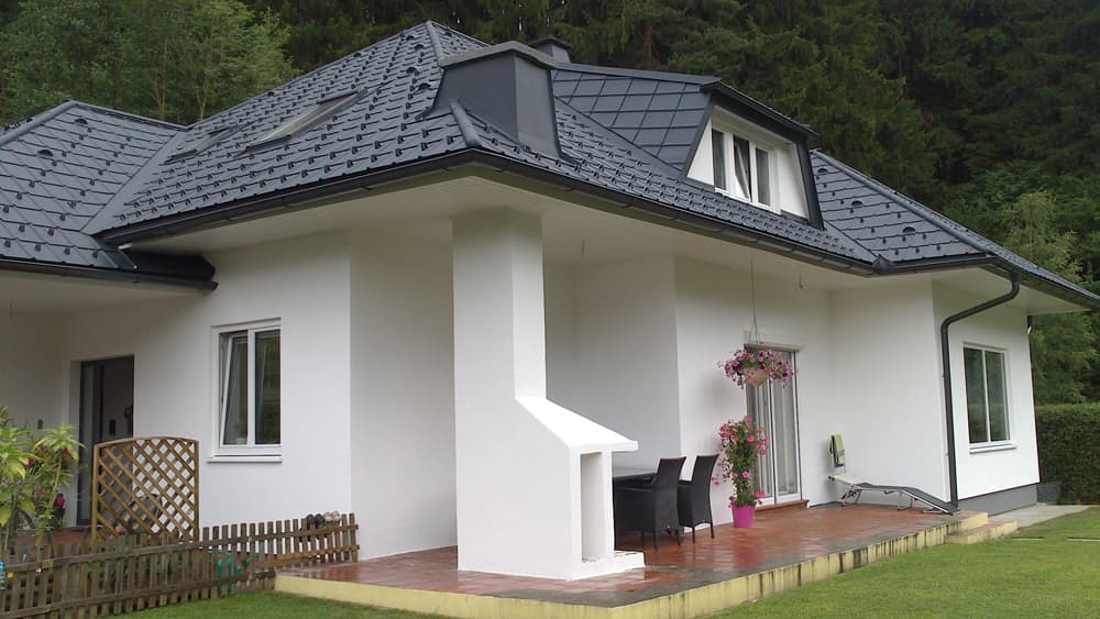 ein kleines weißes Haus mit einem schwarzen Dach